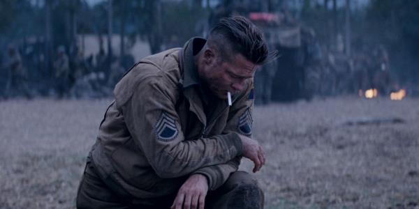 Brad Pitt on one knee with a cigarette in his mouth in Fury.