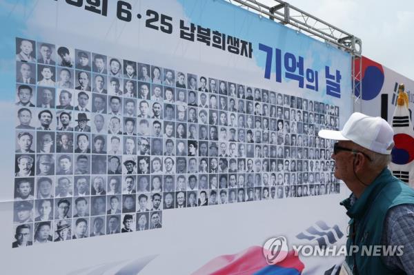 In this file photo, a family member of South Korean victims who were kidnapped by North Korea during the 1950-53 Korean War looks at photos of such abductees in Paju, north of Seoul, on June 28, 2023. (Yonhap)