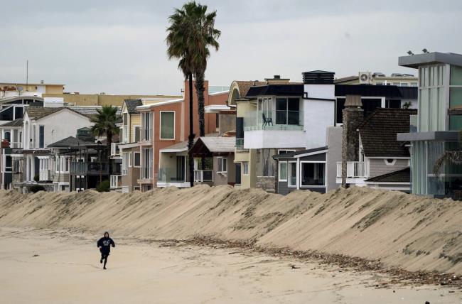 A jogger runs past a large sand berm built to protect low-lying homes from winter storms along the Peninsula neighborhood of Long Beach on Dec. 23, 2019. Photo by Scott Varley, The Orange County Register via AP