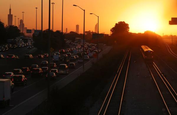 A CTA Blue Line train rolls along as the sun rises over Chicago and the Eisenhower Expressway on Oct. 3, 2023. Weekday service on the system’s two busiest lines, the Red and the Blue, were both cut by a<em></em>bout 20%.